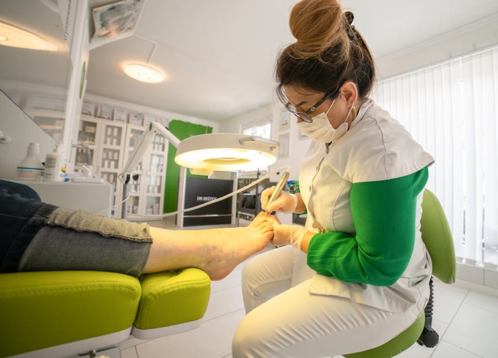 a focused woman doing a pedicure on the foot of a client