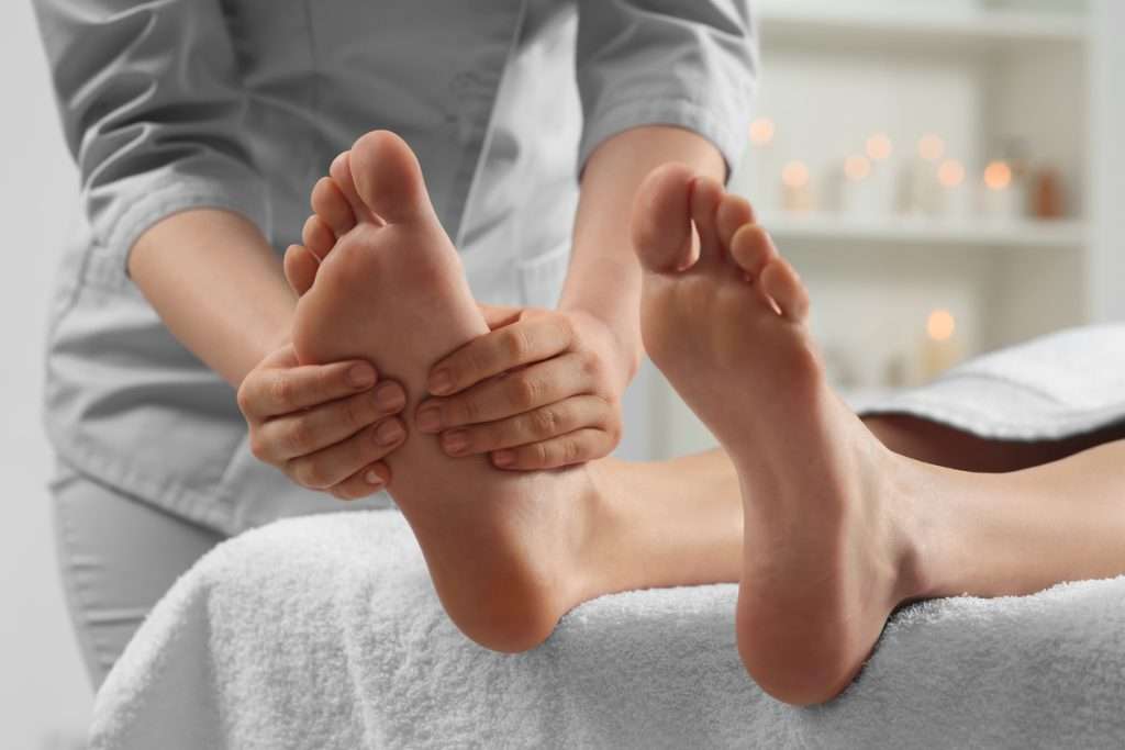 A closeup photo of a therapist massaging patient’s feet