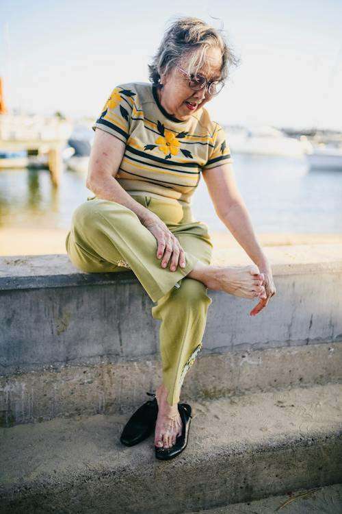 A photo of an elderly woman massaging her foot