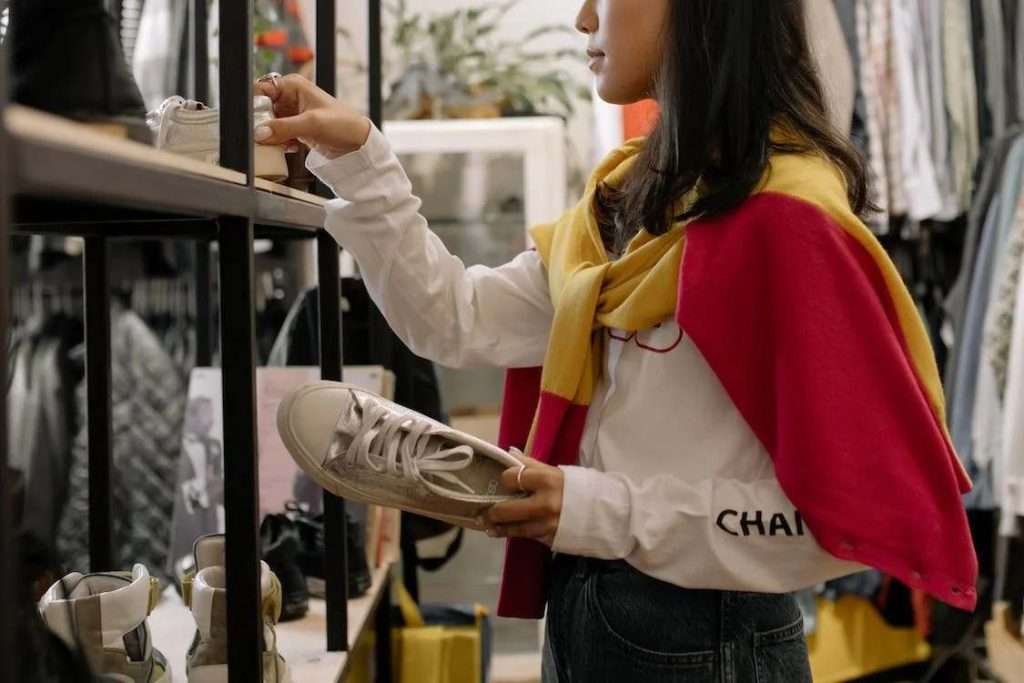 A photo of a woman in white long sleeve shirt and blue denim jeans holding white shoes