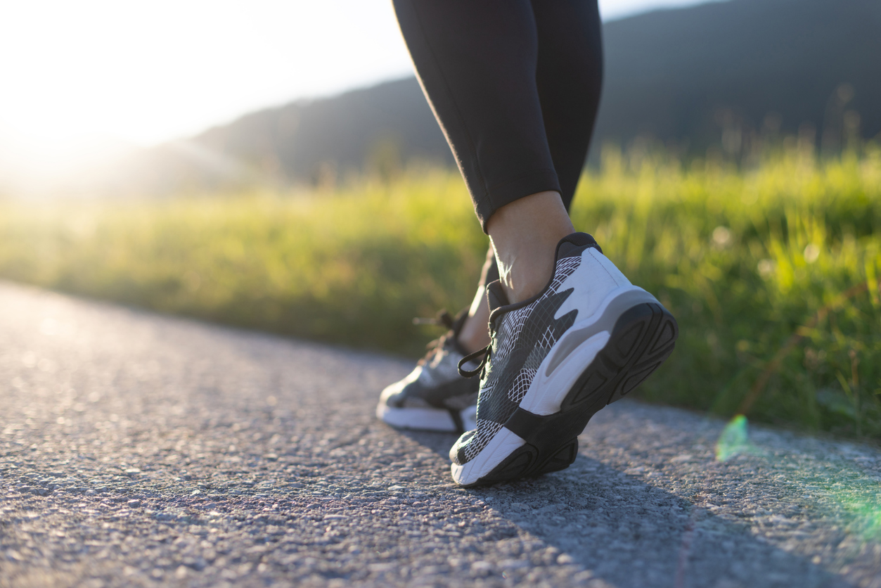 Low section of woman walking on road in mountains